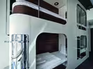Modern bunk beds with white frames and a minimalist design in a modern room. The room has two sets of bunk beds, each with soft bedding and a lovely view of the city.